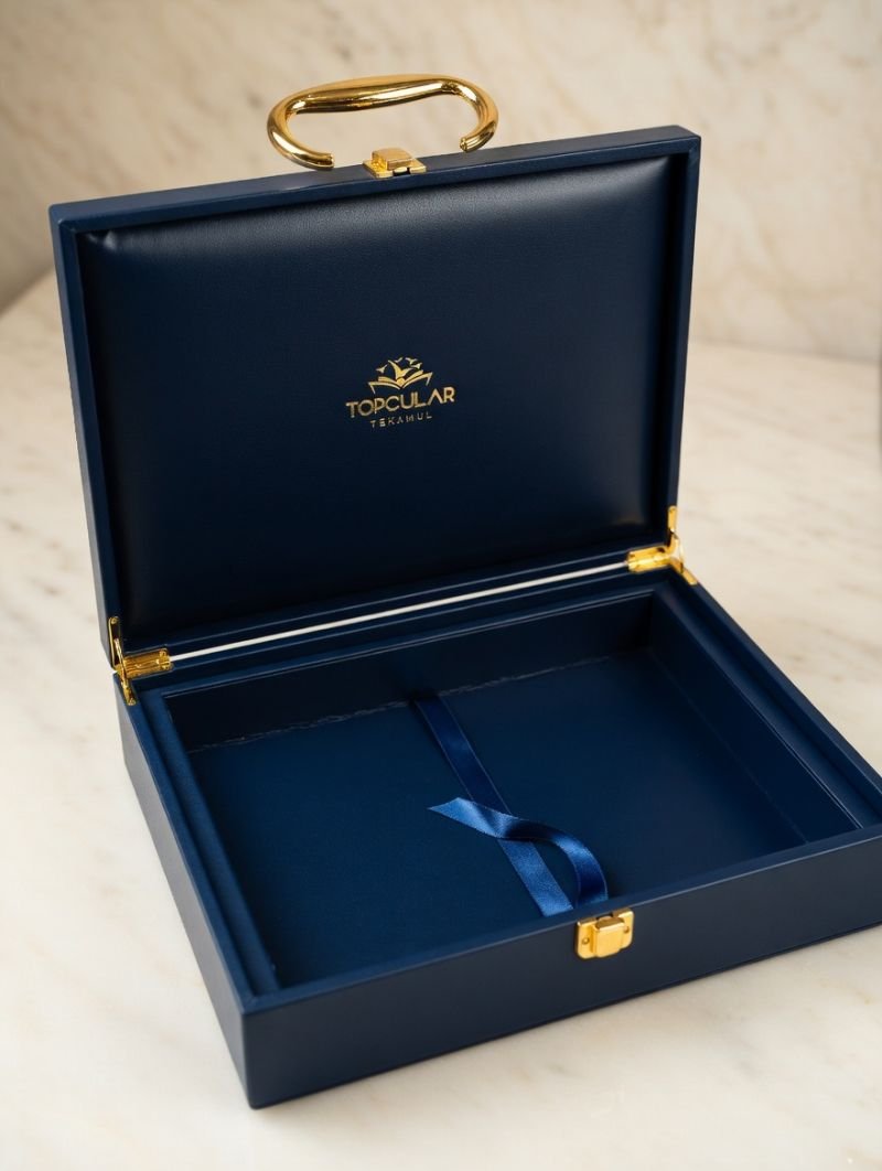 Open navy leather presentation box with gold handle