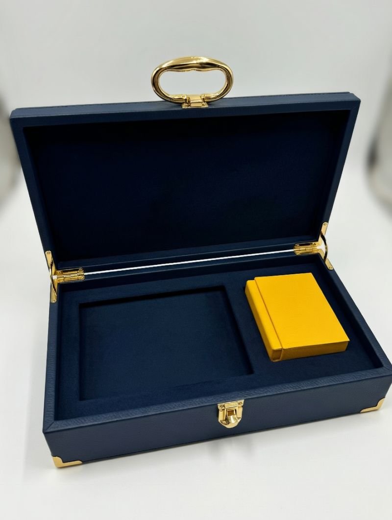 Open navy leather gift box with gold handle and fitted interior