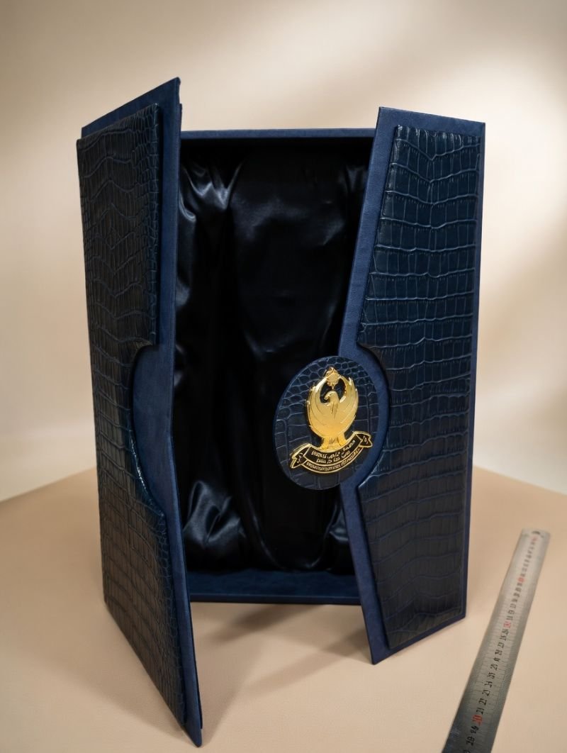 Open navy croc-embossed award presentation box with gold emblem twin leaves
